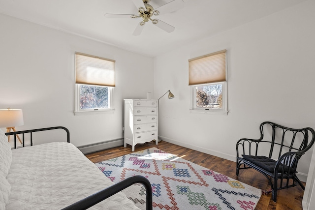 bedroom featuring multiple windows, a baseboard radiator, wood finished floors, and baseboards