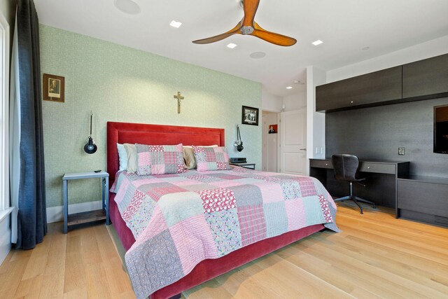 bedroom featuring light hardwood / wood-style floors, ceiling fan, and built in desk