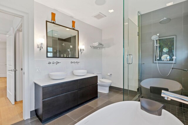 full bathroom featuring vanity, toilet, plus walk in shower, and tile patterned flooring