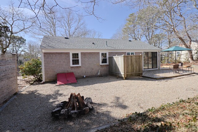 rear view of property with a shingled roof and a wooden deck