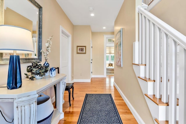 hall with baseboards, light wood-style flooring, stairs, and recessed lighting