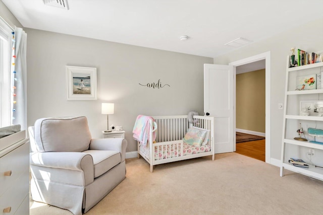 bedroom featuring visible vents, baseboards, a nursery area, and light colored carpet