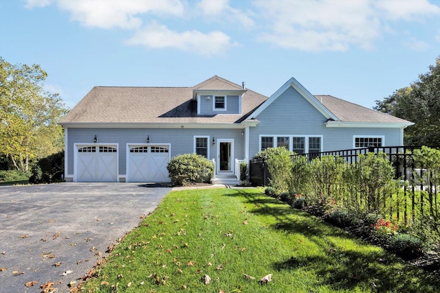 view of front of home featuring a garage, fence, a front lawn, and aphalt driveway