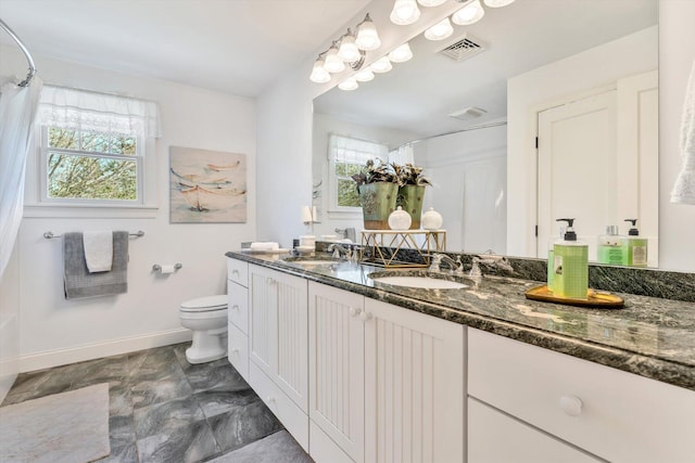 full bath featuring a sink, baseboards, toilet, and a wealth of natural light