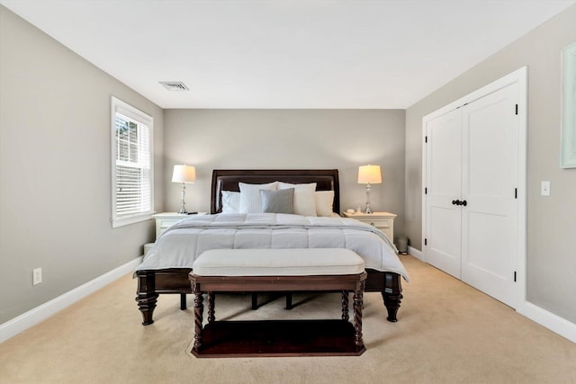 bedroom featuring baseboards, visible vents, light carpet, and a closet