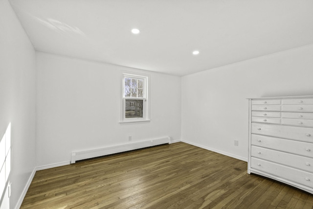 unfurnished room featuring a baseboard heating unit and dark wood-type flooring