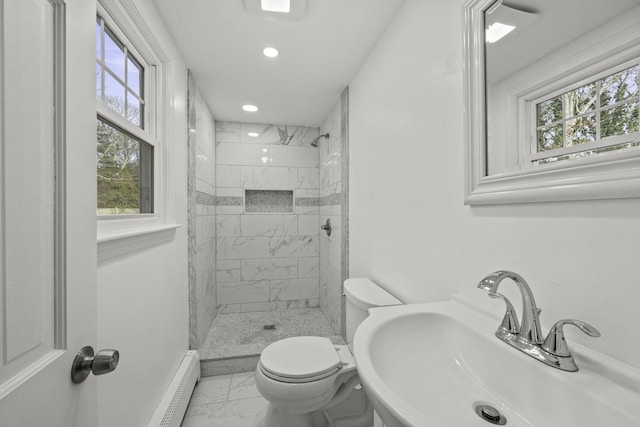 bathroom featuring sink, tiled shower, toilet, and a healthy amount of sunlight