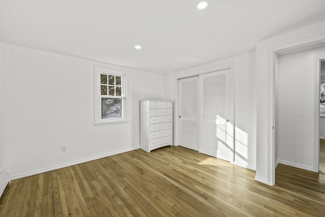 unfurnished bedroom featuring a closet, a baseboard radiator, and wood-type flooring