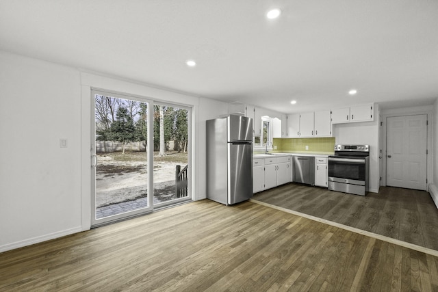 kitchen featuring white cabinetry, sink, backsplash, stainless steel appliances, and dark hardwood / wood-style floors