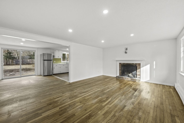 unfurnished living room with a fireplace, a baseboard radiator, and dark hardwood / wood-style flooring