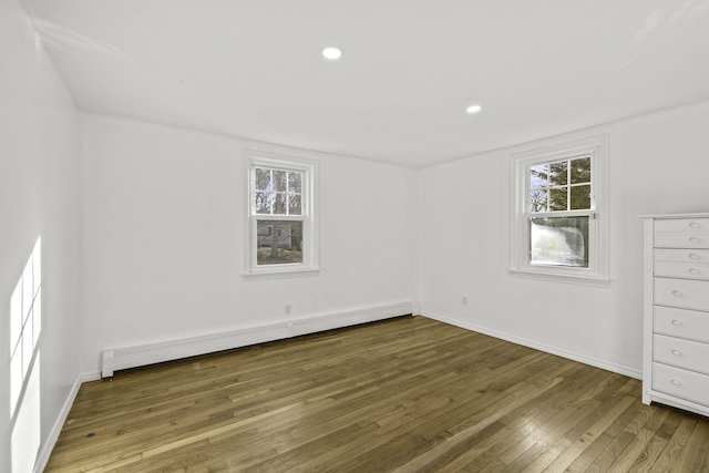 empty room with hardwood / wood-style flooring and a baseboard heating unit