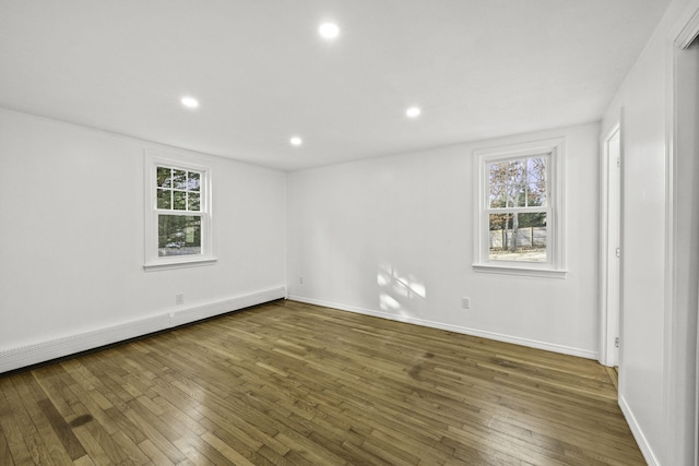 unfurnished room with a baseboard heating unit and dark hardwood / wood-style flooring