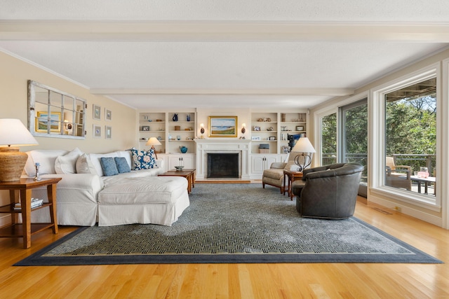 142 Greely Ave, Centerville, MA 02632 - living room featuring beamed ceiling, wood finished floors, crown molding, a fireplace with raised hearth, and built in features