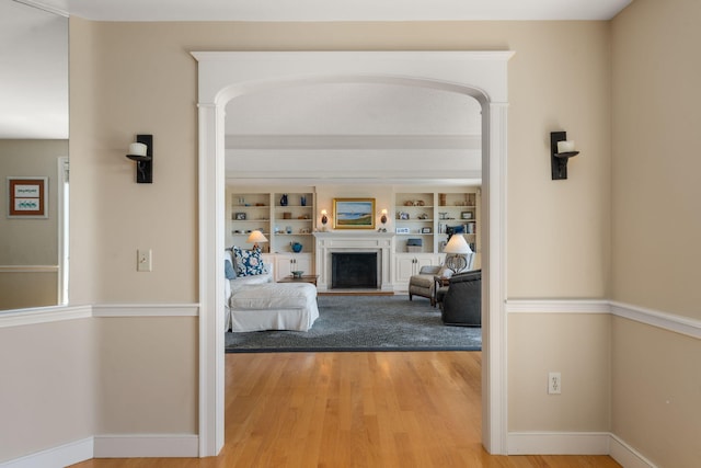 142 Greely Ave, Centerville, MA 02632 - living room with light wood-style floors, a fireplace with raised hearth, arched walkways, and built in shelves