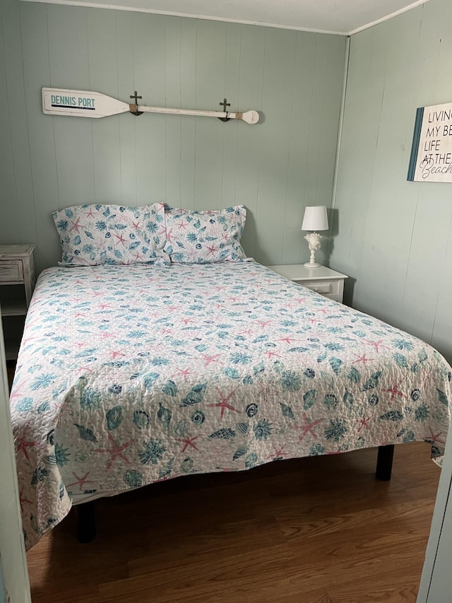 bedroom featuring hardwood / wood-style flooring and wooden walls