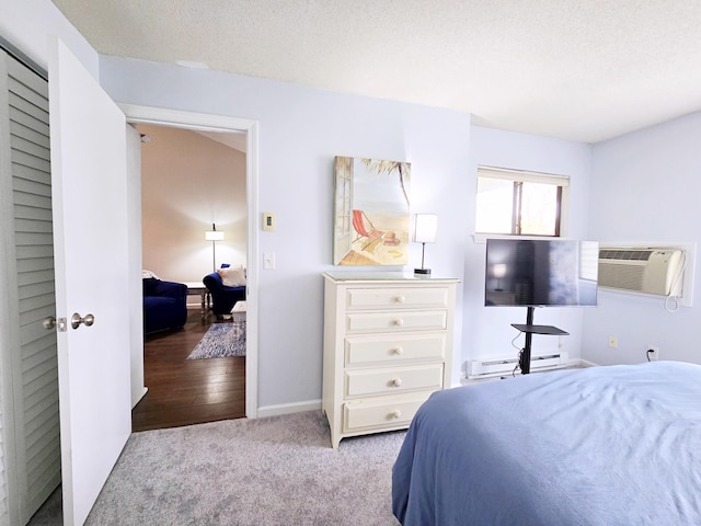carpeted bedroom with a wall unit AC, a baseboard heating unit, and baseboards