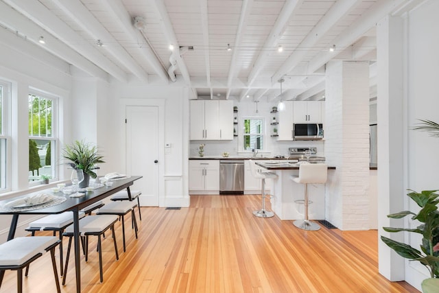 12 Dartmouth St, Hyannis, MA 02601 - kitchen with stainless steel appliances, track lighting, light wood-style flooring, a kitchen breakfast bar, and white cabinetry