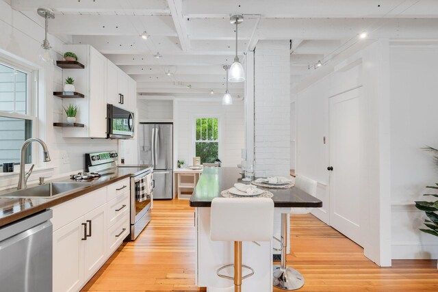 12 Dartmouth St, Hyannis, MA 02601 - kitchen featuring appliances with stainless steel finishes, open shelves, light wood-type flooring, a sink, and white cabinets