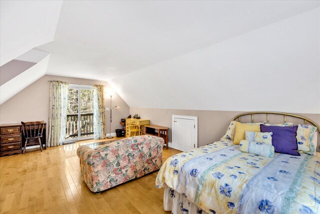 bedroom with access to outside, lofted ceiling, and wood finished floors