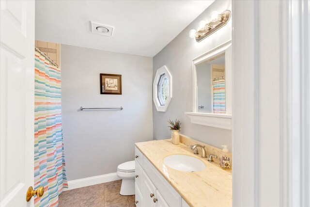 bathroom featuring tile patterned floors, baseboards, vanity, and toilet