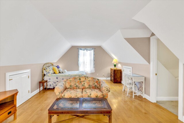 bedroom with baseboards, light wood finished floors, and lofted ceiling