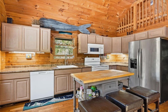 kitchen with lofted ceiling, a sink, wooden walls, butcher block countertops, and white appliances