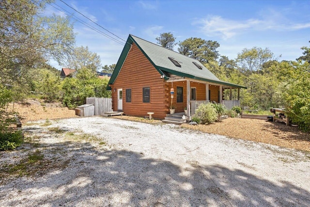 view of front of house featuring covered porch, driveway, and log exterior