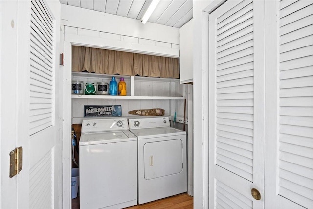 clothes washing area featuring laundry area, wood ceiling, washer and dryer, and wood finished floors