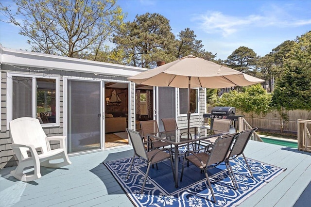 wooden terrace with fence, outdoor dining area, and area for grilling