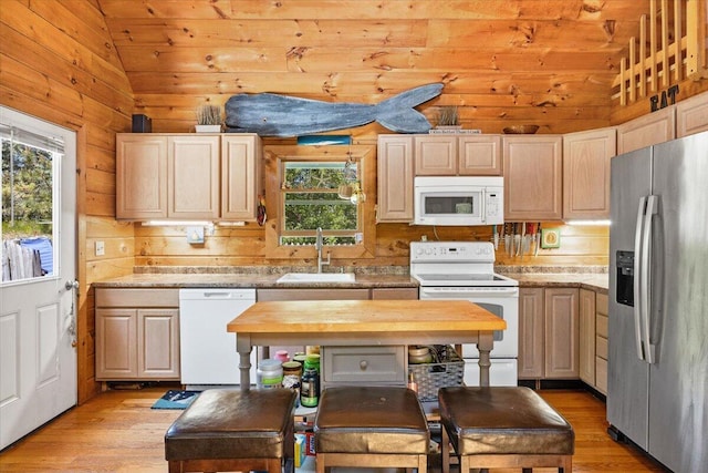 kitchen featuring white appliances, vaulted ceiling, a sink, and light wood finished floors
