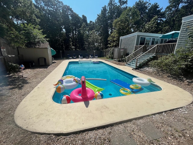 view of pool with a storage shed, a fenced backyard, a fenced in pool, and an outbuilding