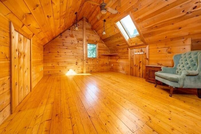additional living space with lofted ceiling with skylight, wood ceiling, wooden walls, and hardwood / wood-style flooring