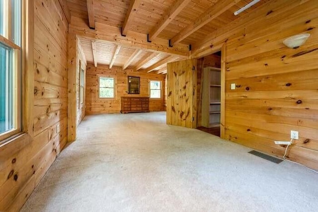 interior space with visible vents, wood ceiling, beamed ceiling, carpet, and wood walls