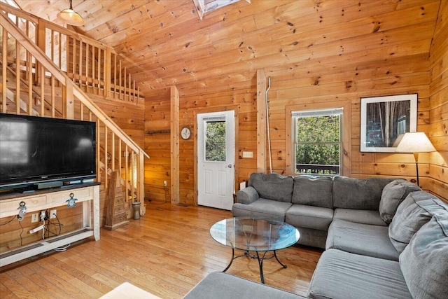 living area with lofted ceiling, wooden ceiling, wooden walls, stairs, and hardwood / wood-style floors