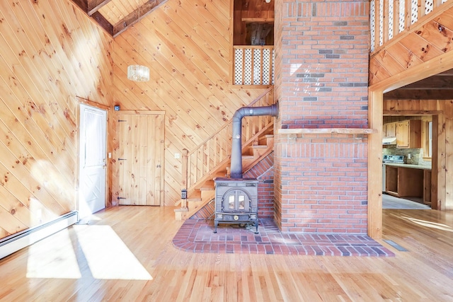 unfurnished living room with high vaulted ceiling, wood walls, beamed ceiling, a baseboard radiator, and a wood stove