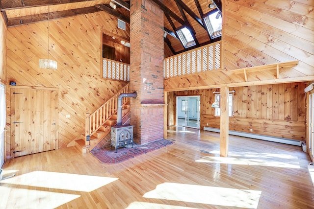 unfurnished living room featuring a baseboard heating unit, wooden walls, and beamed ceiling