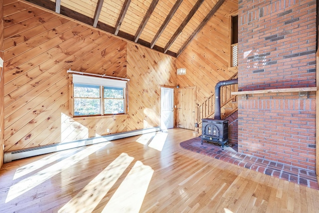 unfurnished living room featuring baseboard heating, wood walls, beamed ceiling, and a wood stove