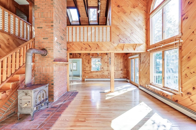 unfurnished living room with wooden walls, a high ceiling, and a baseboard heating unit