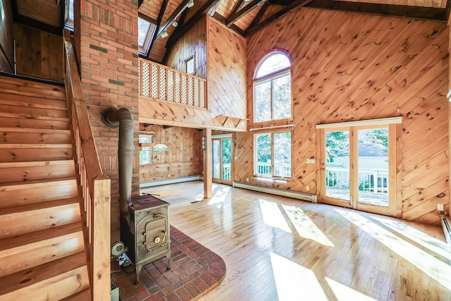 unfurnished living room featuring wood-type flooring, high vaulted ceiling, a baseboard radiator, wooden walls, and beamed ceiling