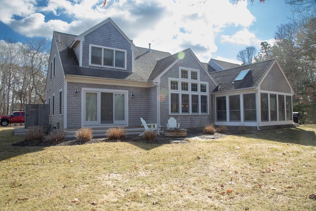 back of property with entry steps, a sunroom, a lawn, and roof with shingles
