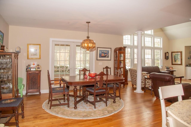 dining space featuring baseboards, french doors, light wood finished floors, and ornate columns