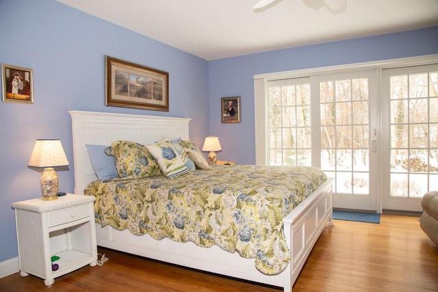 bedroom with access to exterior, multiple windows, and wood finished floors