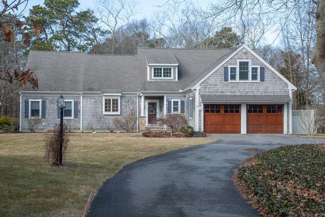 view of front of property featuring a garage, a shingled roof, aphalt driveway, fence, and a front yard