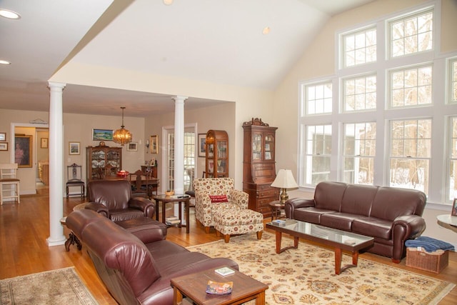living room with high vaulted ceiling, decorative columns, and wood finished floors