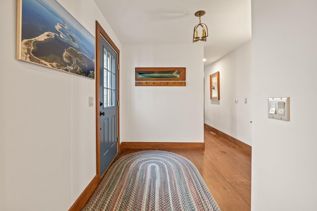 corridor with wood-type flooring and baseboards