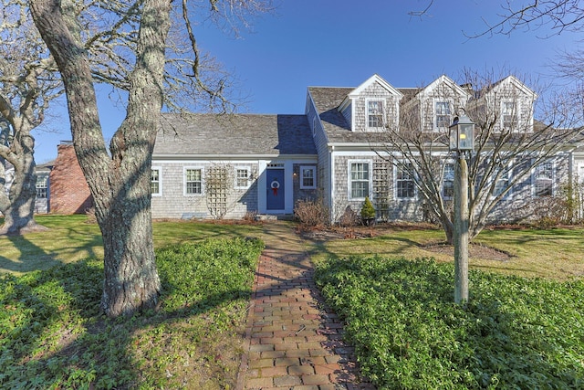 view of front facade featuring a front yard and roof with shingles