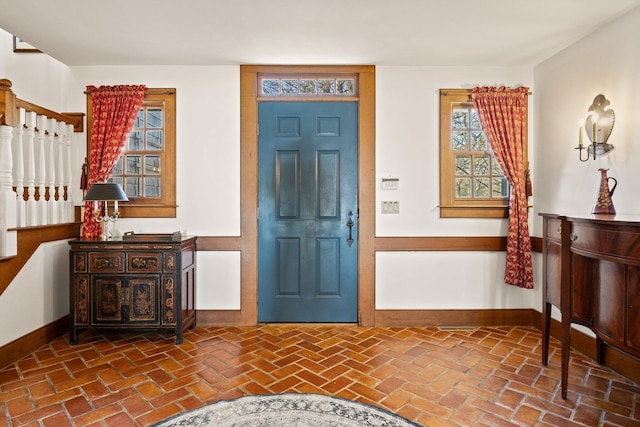 entryway featuring baseboards, brick flooring, and stairway