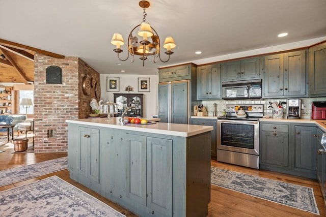 kitchen with stainless steel electric range oven, light countertops, a chandelier, wood finished floors, and decorative light fixtures