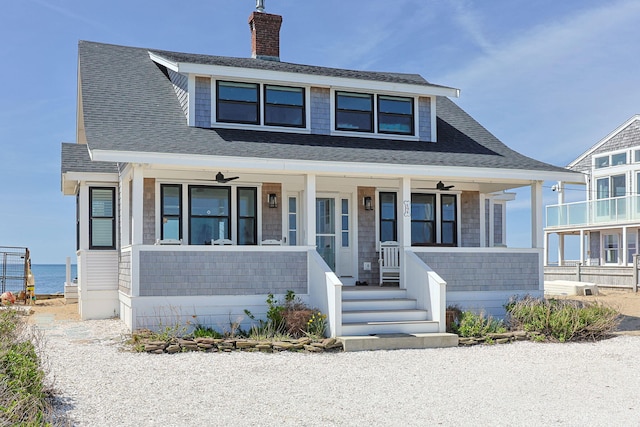 bungalow featuring roof with shingles, a chimney, and a porch