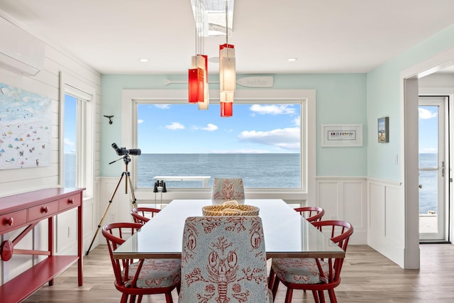 494 Shore Rd, North Truro, MA 02652 - dining space with a water view, a decorative wall, a wainscoted wall, and wood finished floors